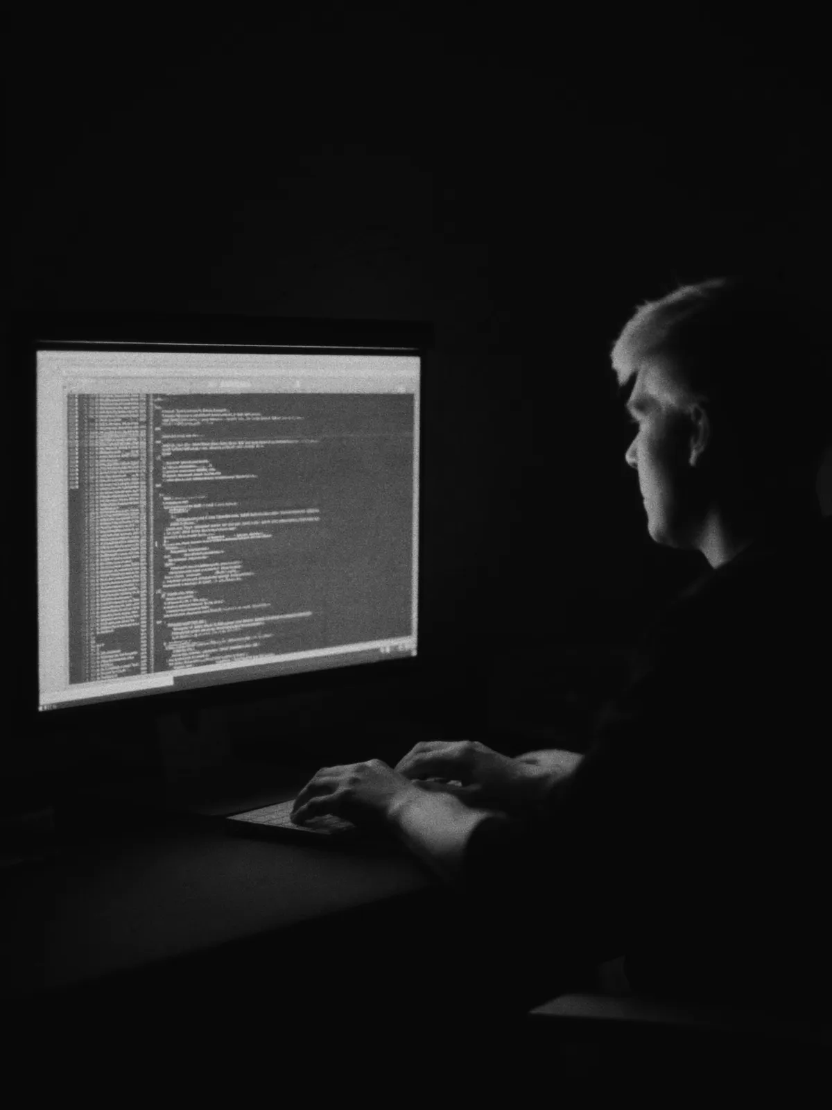 A developer working late, lit by a screen of code